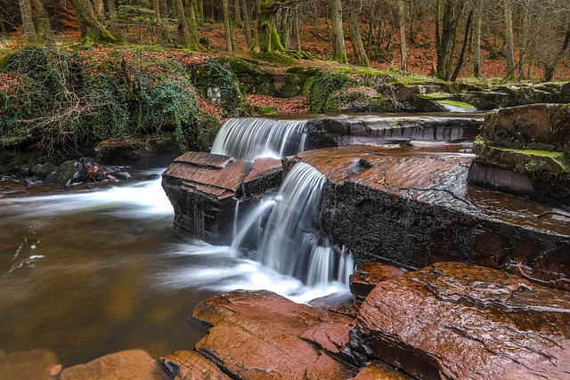 A peaceful waterfall flows over layered rocks