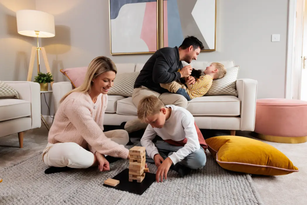 A family happily playing with wooden blocks on the floor.