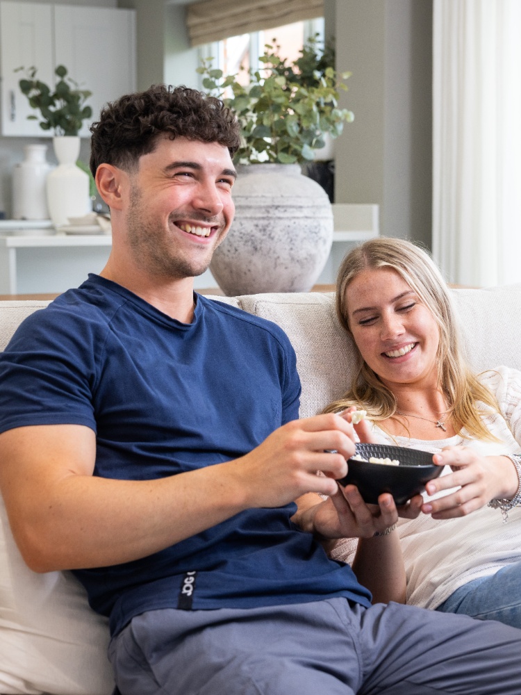 Couple on the sofa sharing popcorn in new home